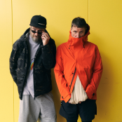 Artist Sleaford Mods standing in front of a yellow wall